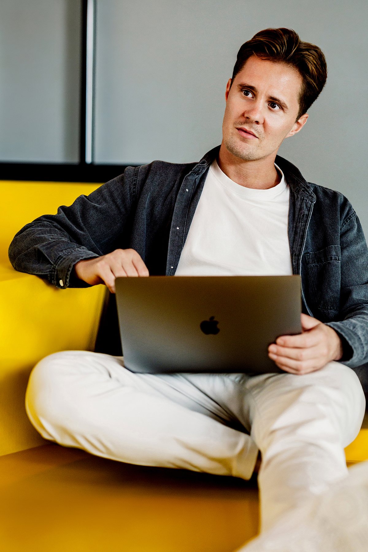 Tom Hoetink op de gele bank met zijn laptop
